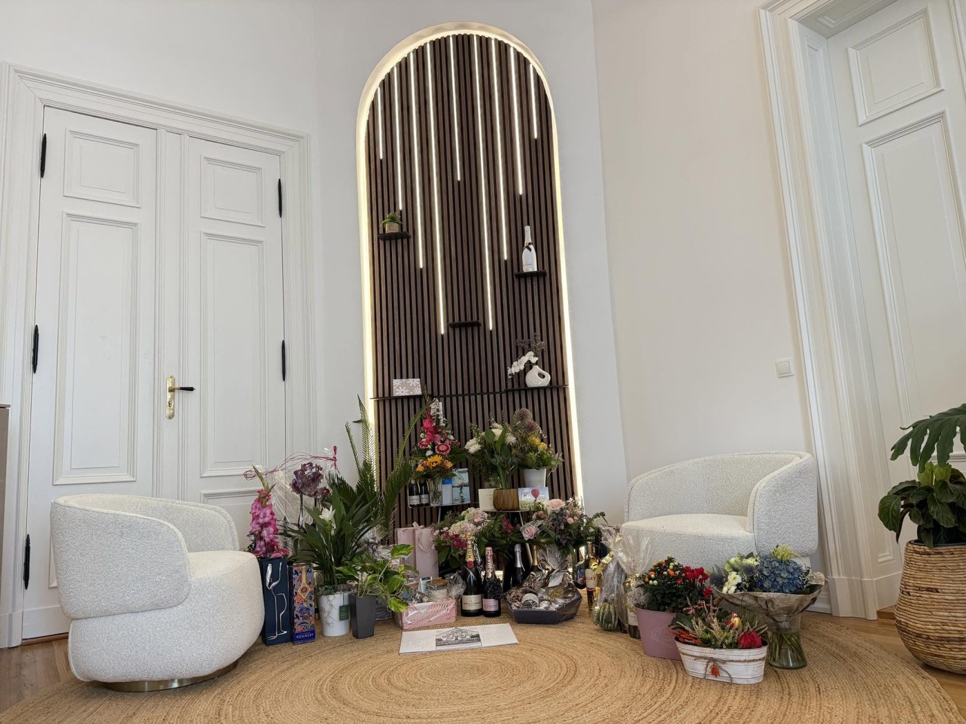 Blumen und Geschenke zur Einweihung vor der beleuchteten Holzwand im Empfangsraum