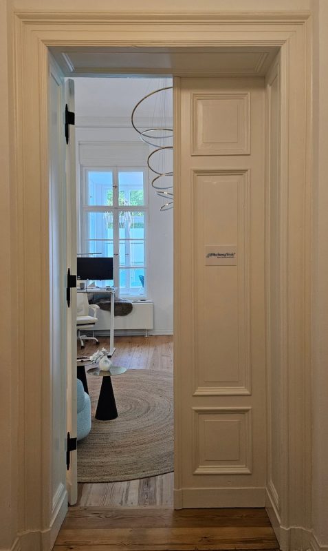 Durchblick durch eine Flügeltür in den hellen Empfangsraum